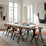 Modern dining room with a long table and chairs, large windows, and abstract art on the walls.
