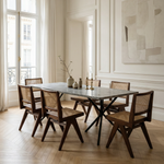 Dining room with marble table and wooden chairs in a well-lit room.