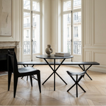 Dining room with a black table and chairs in a bright room with large windows.