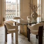 Dining room with a glass table and upholstered chairs in a stylish interior.
